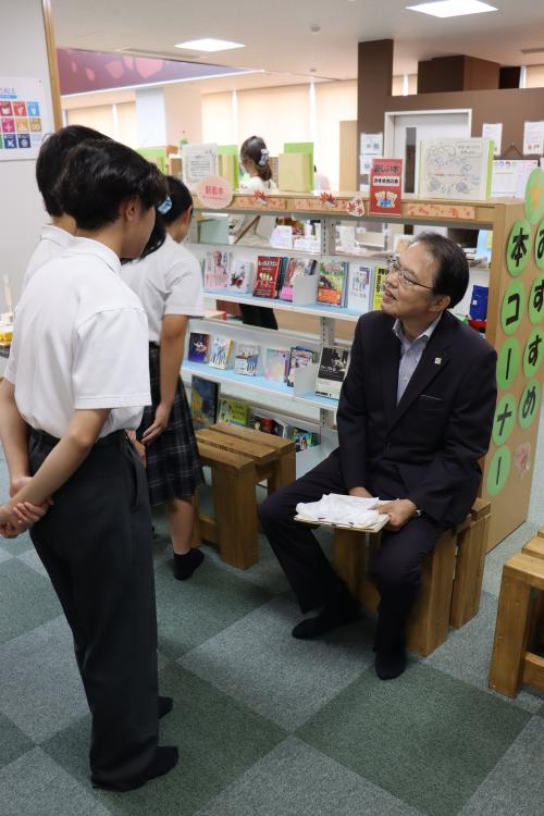 生徒手作りいすに座って談話する佐藤町長