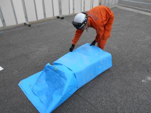 レジャーシートでポリタンクを巻き込む様子
